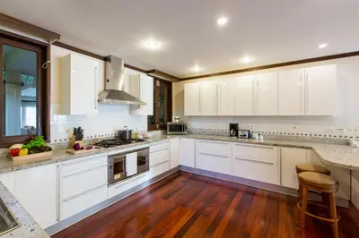 a kitchen with white cabinets and a wooden floor at Katamanda Kata View villa E5 near kata Noi Beach in Kata Beach