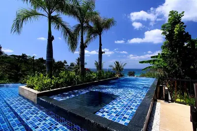 a swimming pool with palm trees and the ocean at The heights Kata seaview C1 near Kata Beach in Kata Beach