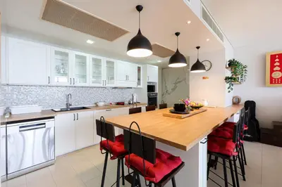 a kitchen with white cabinets and a wooden island with red chairs at The heights Kata seaview C1 near Kata Beach in Kata Beach