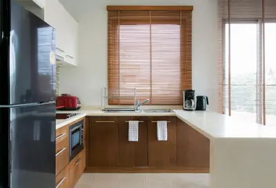 a kitchen with wooden cabinets and a stainless steel refrigerator at Kata Gardens Penthouse sea view 4C near Kata Noi Beach in Kata Beach