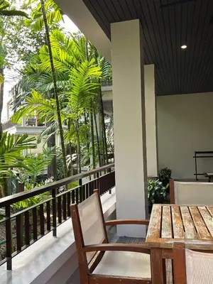 a table and chairs on a balcony with palm trees at Kata Gardens Luxury Apartment 8B at Kata Noi Beach in Kata Beach