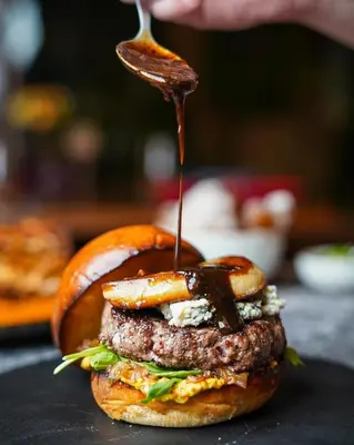 a hamburger with a sauce being drizzled on it at Kata Gardens Luxury Apartment 8B at Kata Noi Beach in Kata Beach