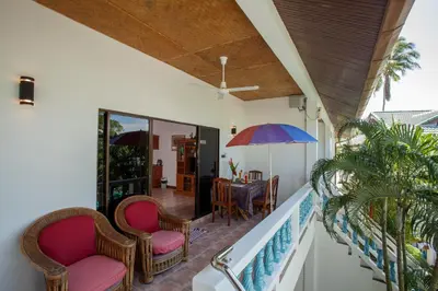 a balcony with chairs and a table with an umbrella at Ya Nui Resort - SHA EXTRA Plus in Rawai Beach