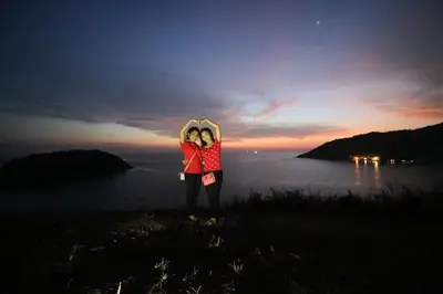two people standing on top of a hill near the water at Ya Nui Resort - SHA EXTRA Plus in Rawai Beach