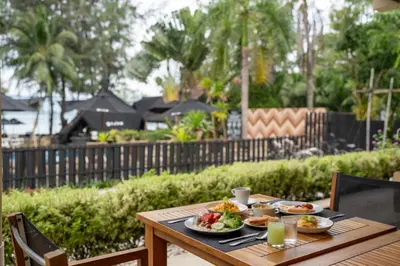 a wooden table with plates of food on it at The Mangrove Phuket by Blu Monkey in Panwa Beach