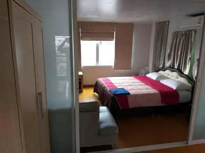 a bedroom with a bed and a chair and a window at Baan Malee in Phuket Town