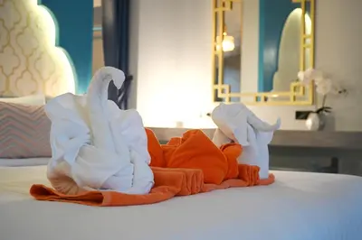 two swans sitting on a bed in a hotel room at The Kiri Villas Resort in Thalang