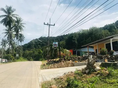 an empty road with a building and palm trees at Koh Yao Candy House in Ko Yao Yai