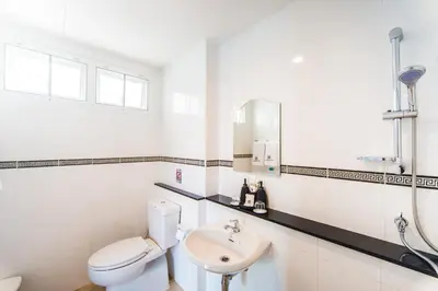 a white bathroom with a toilet and a sink at Peranakan Boutique Hotel - SHA Plus in Phuket Town