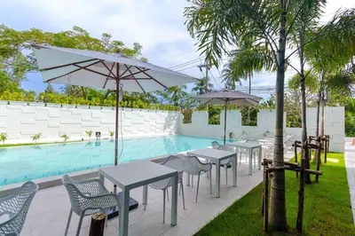 a group of tables and chairs with umbrellas next to a pool at Oceanstone by Holy Cow, 2-BR, 75 m2, garden view in Bang Tao Beach