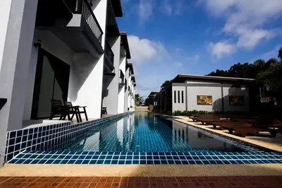 a swimming pool in front of a building at Alphabeto Resort in Nai Harn Beach