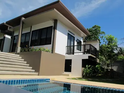 a house with a swimming pool in front of it at Alphabeto Resort in Nai Harn Beach