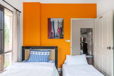 two beds in a room with an orange wall at Sea eagle pool villa in Ao Nang Beach
