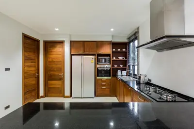 a kitchen with wooden cabinets and a white refrigerator at Villa Palavee (B2) in Ao Nang Beach