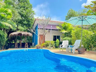 a swimming pool with two chairs and an umbrella at Canal Resort in Nai Yang Beach