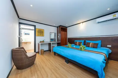 a bedroom with a blue bed and a chair at Phi Phi Long Beach Bungalow ( Had Yao) in Phi Phi Don