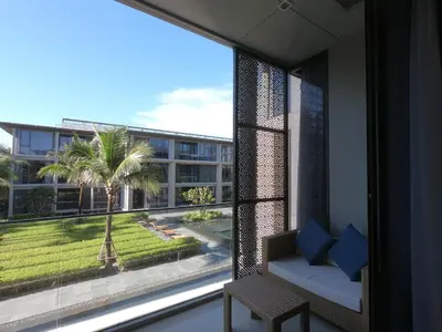 a room with a large window with a couch and a palm tree at Baan Mai Khao condo in Mai Khao Beach