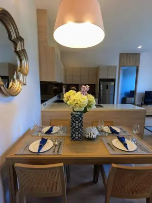 a dining room table with a vase of flowers on it at Baan Mai Khao condo in Mai Khao Beach