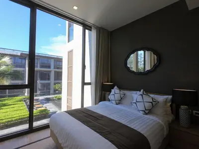 a bedroom with a large bed and a large window at Baan Mai Khao condo in Mai Khao Beach