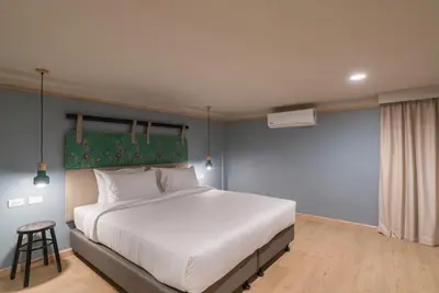 a bedroom with a large white bed and a stool at The Blanket Hotel Phuket Old Town in Phuket Town