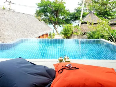 a swimming pool with an orange pillow next to a red raft at JJ Queen Villa and Spa Kohyaonoi in Ko Yao Noi
