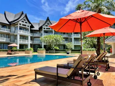 a group of chairs and umbrellas next to a pool at Allamanda Laguna Phuket by RESAVA in Bang Tao Beach