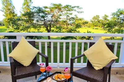 two wicker chairs with a tray of food on a balcony at Allamanda Laguna Phuket by RESAVA in Bang Tao Beach