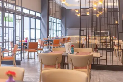 a dining room with tables and chairs and windows at WOOVO Phuket Patong - by Swandor in Patong Beach