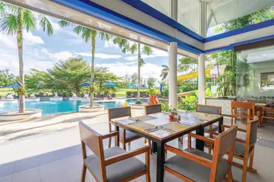 a dining room with a table and chairs and a swimming pool at Homm Suites Laguna, part of Banyan Group in Bang Tao Beach