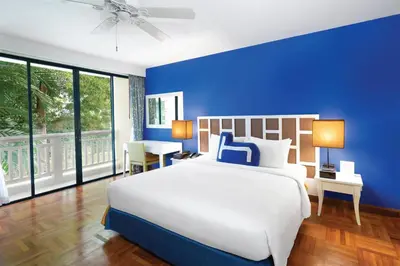 a blue bedroom with a white bed and a blue wall at Homm Suites Laguna, part of Banyan Group in Bang Tao Beach