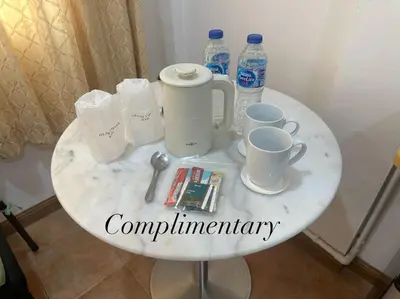 a white table with cups and water bottles on it at Surin Bay Inn in Surin Beach