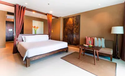 a bedroom with a large bed and a table at SUNSURI PHUKET, Nai Harn Beach in Nai Harn Beach