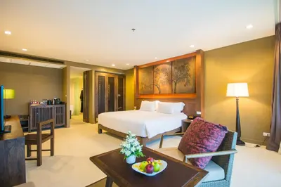 a hotel room with a bed and a living room at SUNSURI PHUKET, Nai Harn Beach in Nai Harn Beach