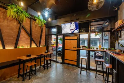 a restaurant with a bar with stools and tables at The Z Nite Hostel in Phuket Town
