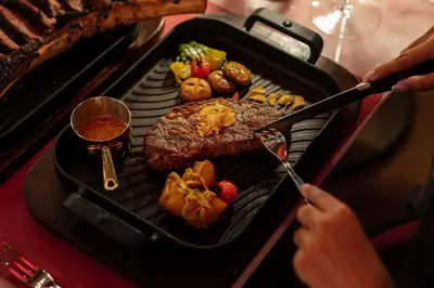 a person is cooking food on a grill at Katathani Phuket Beach Resort - SHA Extra Plus in Kata Beach