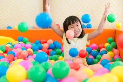 a little girl playing in a pile of balls at Katathani Phuket Beach Resort - SHA Extra Plus in Kata Beach