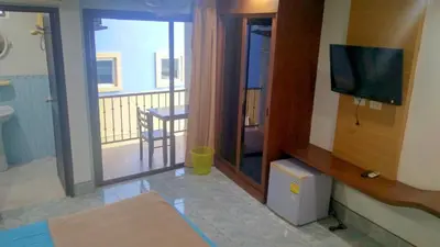 a room with a bed and a television and a balcony at Baan Ketkeaw Guest House 2 in Patong Beach