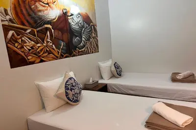 two beds in a room with a painting on the wall at Phuket Old Town Hostel in Phuket Town