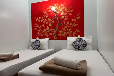 two beds in a room with a painting on the wall at Phuket Old Town Hostel in Phuket Town