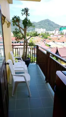 a balcony with two white chairs and a tree at U Sabai Living Hotel in Patong Beach