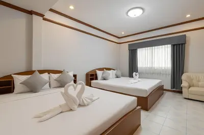 a hotel room with two beds and a chair at Break Point Patong Hotel in Patong Beach