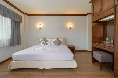 a bedroom with a large white bed and a desk at Break Point Patong Hotel in Patong Beach