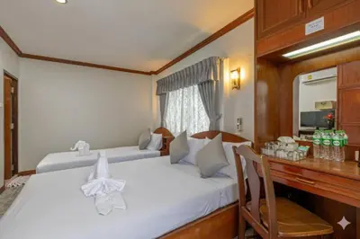 a bedroom with two beds and a desk with a mirror at Break Point Patong Hotel in Patong Beach