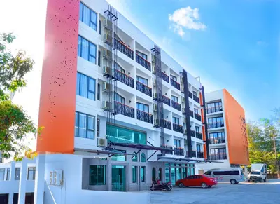 a white building with a red car parked in front of it at Phoenix Hotel Karon Beach in Karon Beach
