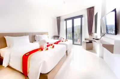 two beds in a hotel room with stuffed animals on them at Phoenix Hotel Karon Beach in Karon Beach