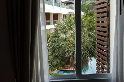 a view of a palm tree from a window at Sunset Bliss in Klong Muang Beach