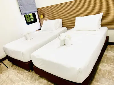 two beds in a hotel room with white sheets at Siray Green Resort in Phuket Town
