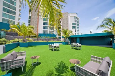 a patio with tables and chairs on a lawn with buildings at Oceana Sea View Apartments - Kamala Beach in Kamala Beach