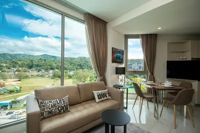 a living room with a couch and a large window at Oceana Sea View Apartments - Kamala Beach in Kamala Beach