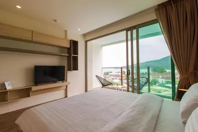 a hotel room with a bed and a large window at Oceana Sea View Apartments - Kamala Beach in Kamala Beach